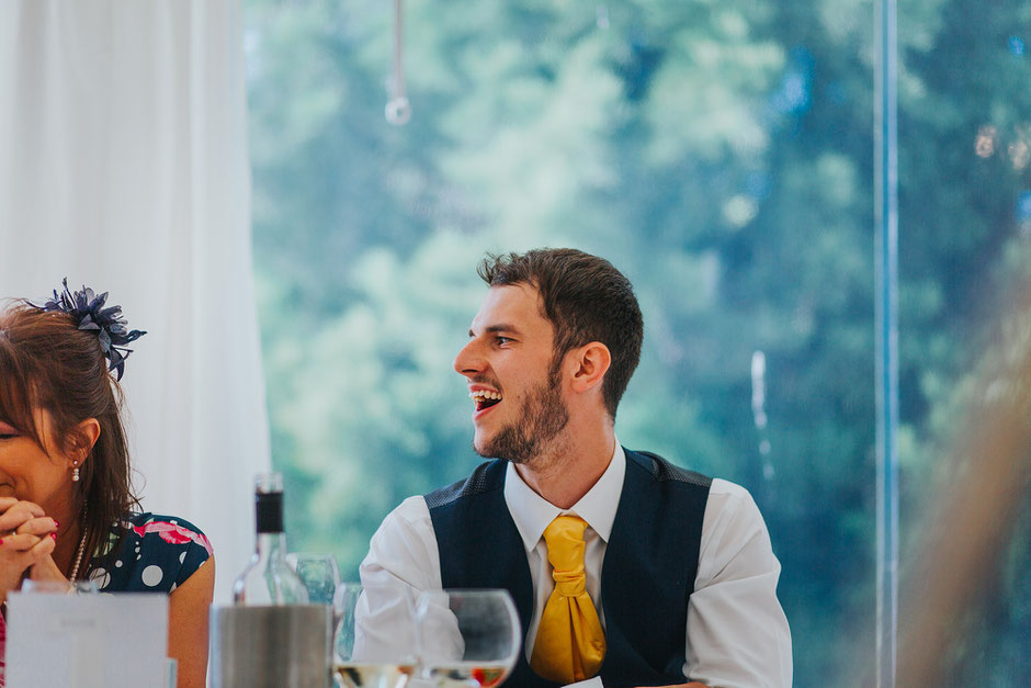 best man laughing in a marquee during wedding speeches