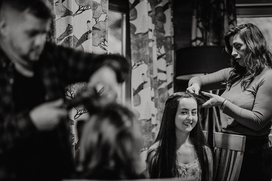 black and white photograph of two bridesmaids smiling at each other having their hair done