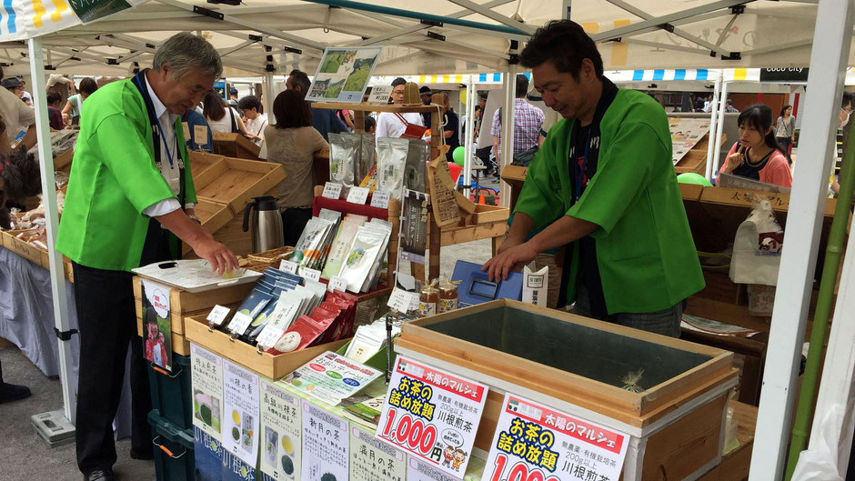 「太陽のマルシェ」(中央区勝どき)で出会った、樽脇園(たるわきえん)の樽脇靖明さん。お店の様子。黄緑のハッピが目立つ。お二人の掛け合いもにぎやかでおもしろい。