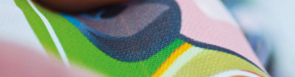 Detailaufnahme eines bunten Stoffmotivs im Sublimationsdruck mit klaren Farbverläufen in Grün, Blau, Rosa und Gelb.