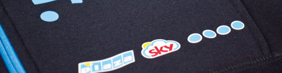 Nahaufnahme eines schwarzen Stoffes mit aufgebrachtem Siebdruck-Transfermotiv in Blau, Weiß, Gelb und Rot.