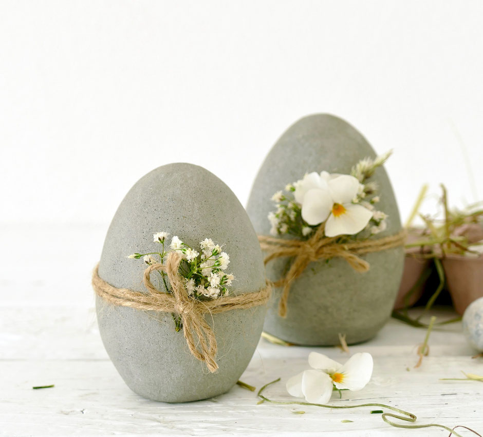 Selbst gemachte Ostereier aus Beton mit Schnur und Blüten verziert