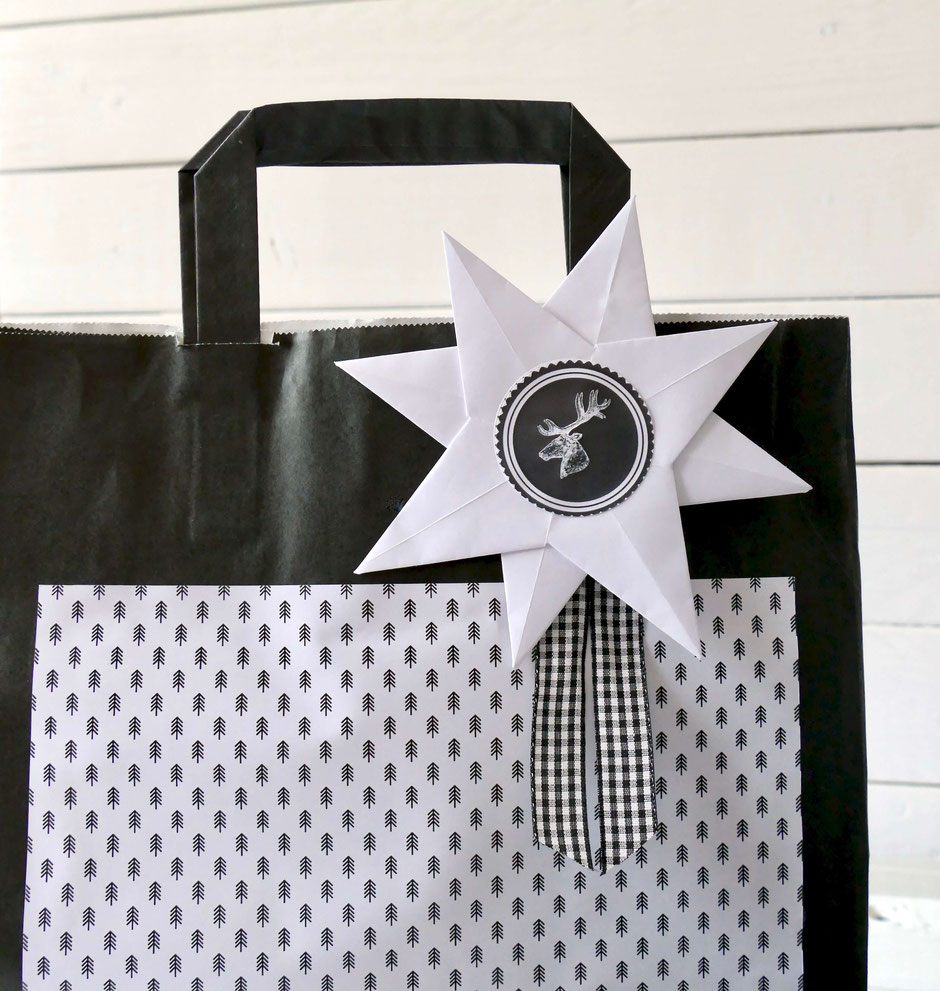 Schwarze Papier Tragetasche mit gefaltetem Papierstern Hirschmotiv