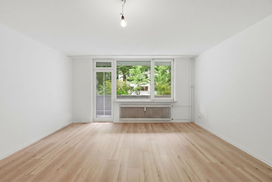 Wohnbereich der 1-Zimmer-Wohnung in Zehlendorf mit hellem Laminat und Balkonzugang