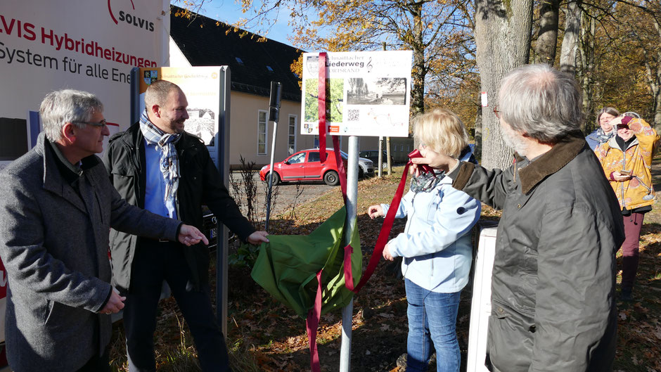 Brückner, Pitterlein, Bauer und Junga (v.l.) enthüllen die Stationstafel des Liederwegs beim Badsaal