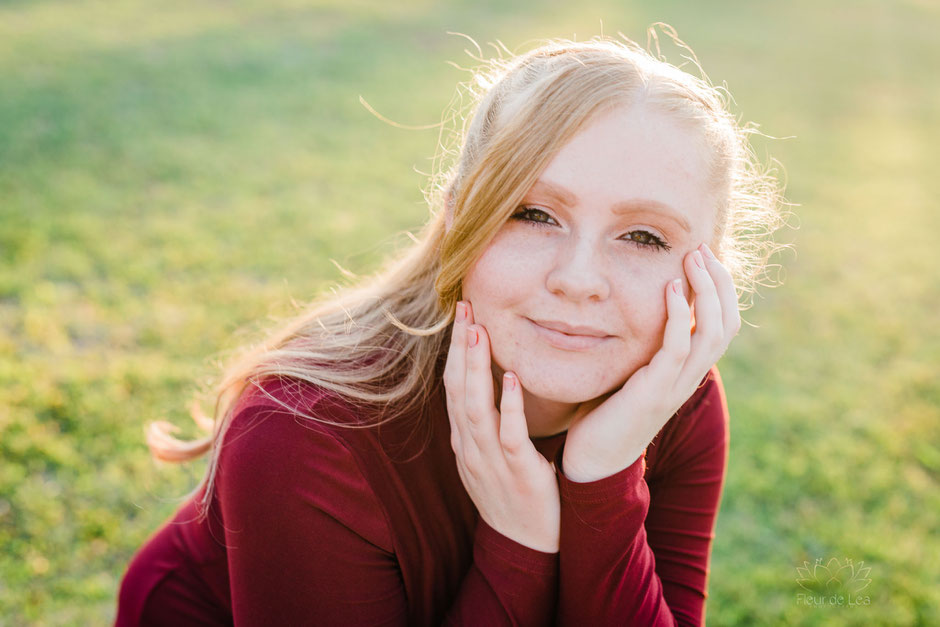 senior girl with strawberry blonde hair and red dress sun shining on senior session. Fleur de Lea Photography
