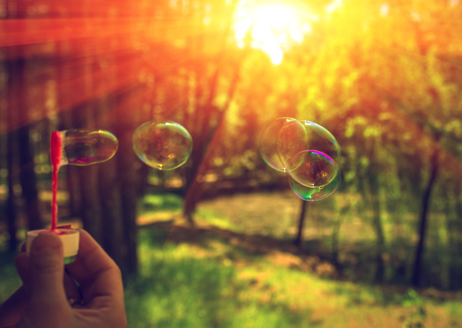 Seifenblasen pusten im Wald mit Sonnenstrahlen