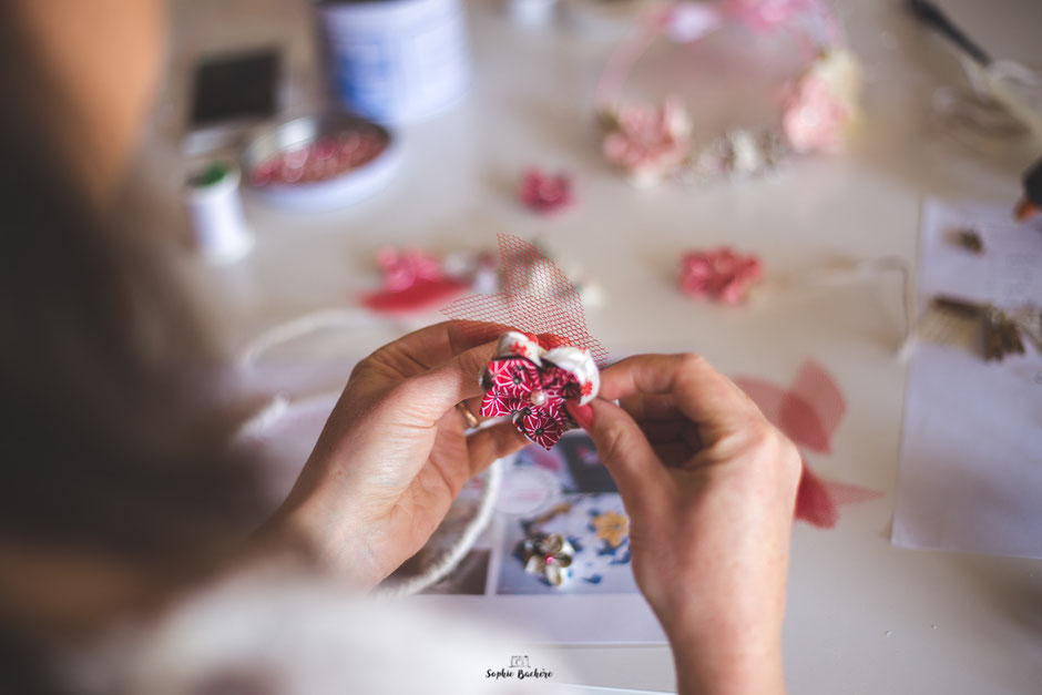 Confection artisanale d'une couronne de fleurs en tissus et papiers pour un mariage thème Japon en rose, rouge et blanc par La mariée en fleur. Crédit photo: Sophie Bachère