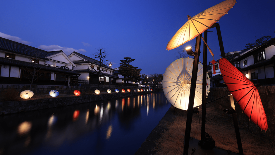 夜の川面に映るライトアップされた和傘