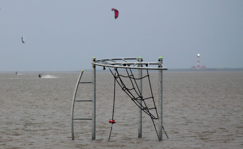 Bild: Sturmflut in St. Peter-Ording: Kitesurfer surfen zwischen Spielgeräten auf dem überfluteten Strand (Foto: Karena Hoffmann-Wülfing)