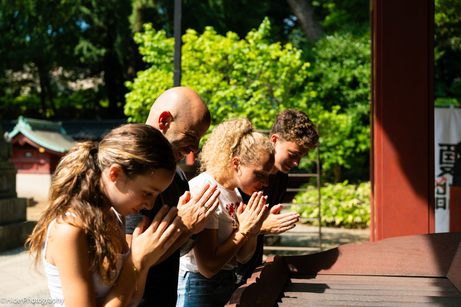 Family praying together at Nezu Shrine during a cultural photography experience in Tokyo