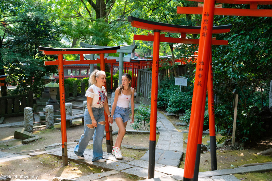 Family walking through the red torii gates of Nezu Shrine during a morning photography experience in Tokyo
