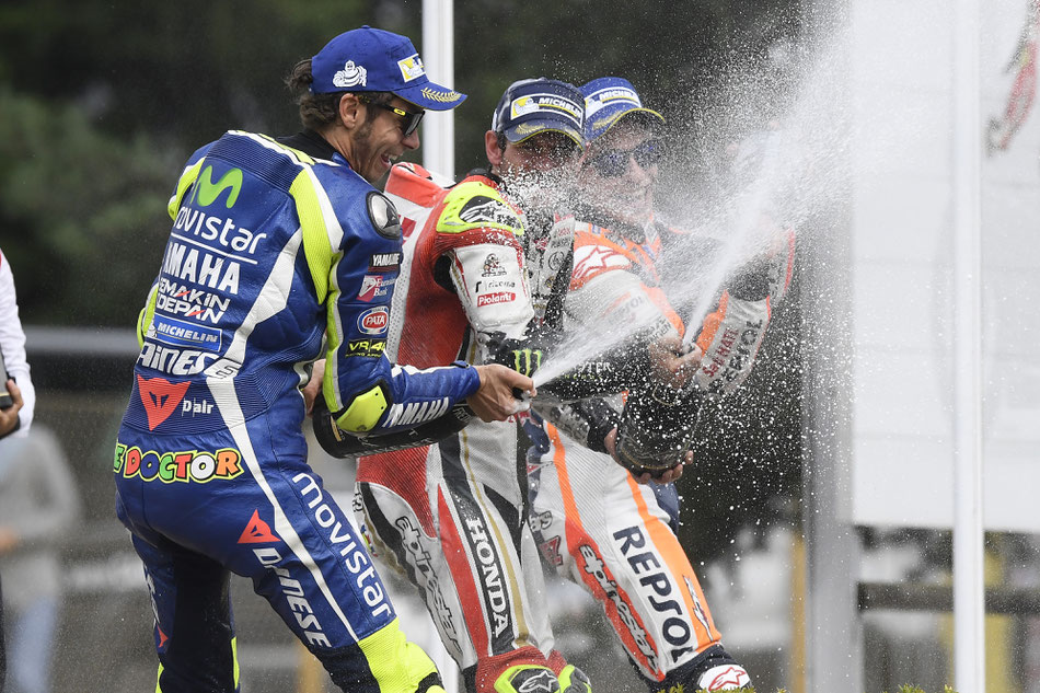 Sieger unter sich. Cal Crutchlow lässt mit Valentino Rossi und Marc Marquez die Champagnerkorken knallen.