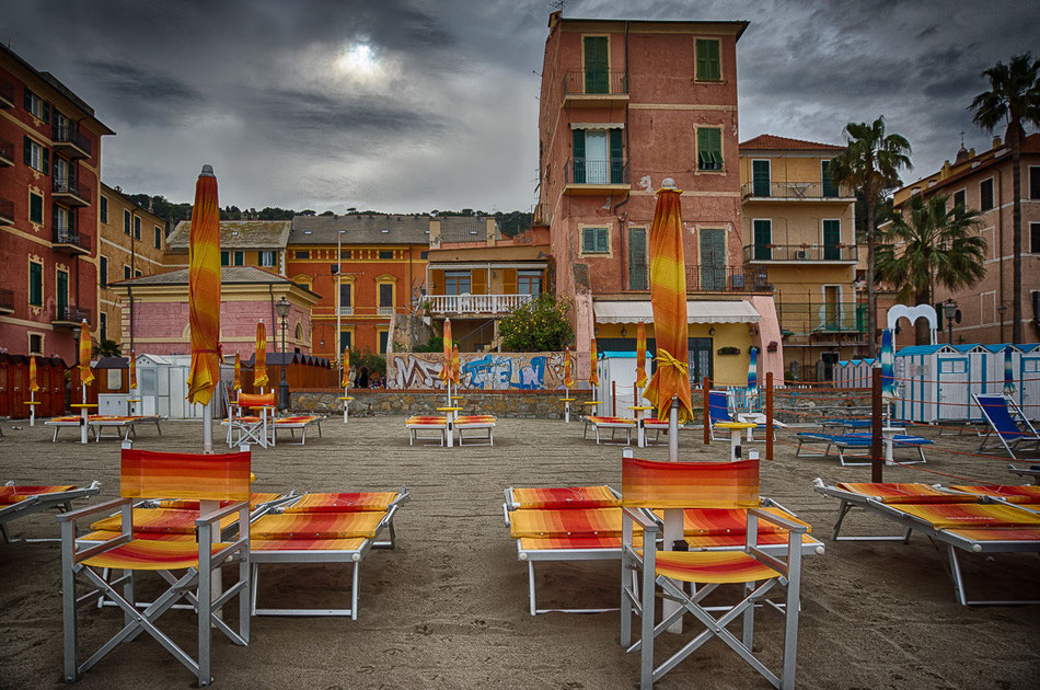 Strand von Alassio, Riviera, orangene Hotelgebäude und Sonnenliegen, Italien