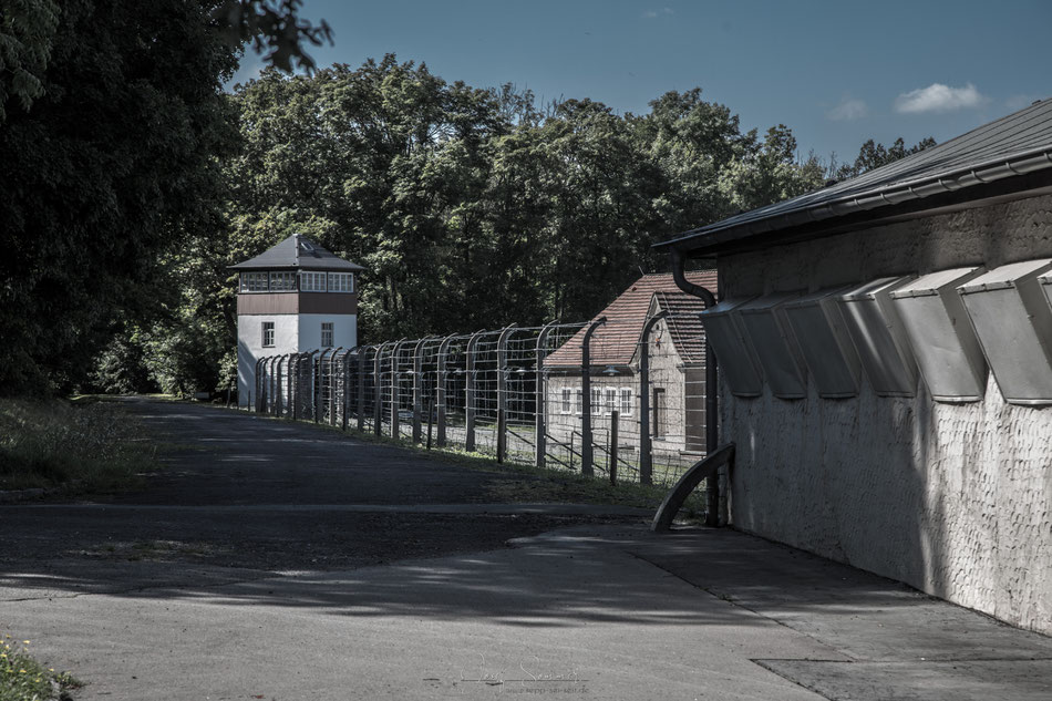 Wachturm mit Stacheldrahtzaun und der Arrestzelle "Bunker" - einer Mord- und Folterstätte des Lagers