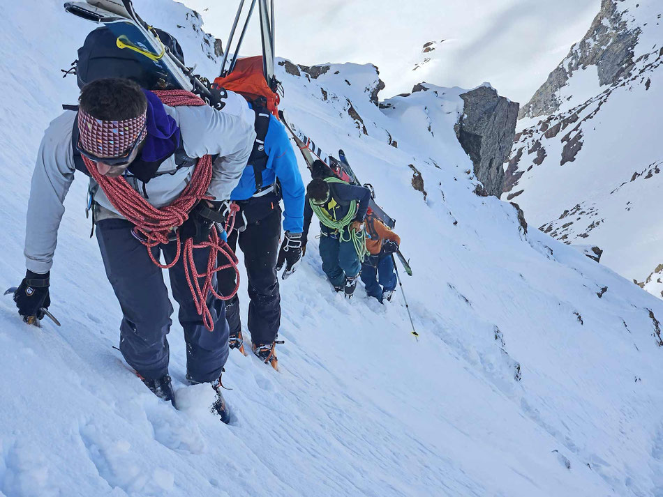Skitourengruppe beim Aufstieg in steilem Gelände im Schnee in den Bergen