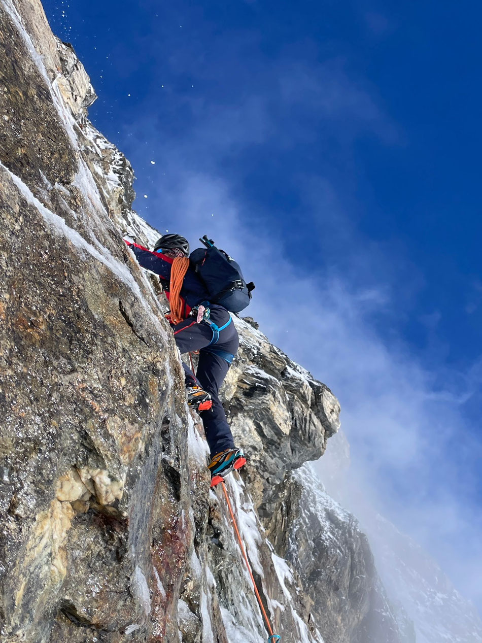 Bergführer beim Aufstieg in der steilen Felswand auf dem Weg zum Gipfel, gesichert mit einem Seil