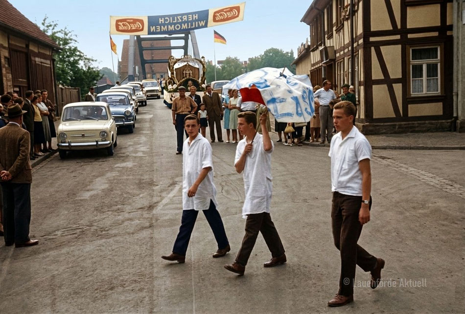 1967 Sportfest Lauenförde. Hier, Umzug aus der Langen Strasse kommend, Stau auf der Brücke. Fehler bei der Kolorierung, Tischlerei Brümmer hatte damals bereits Schaufenster.