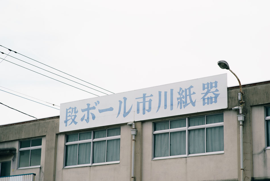 写真：市川紙器外観。市川紙器製作所です。山梨県の甲府市に本社と工場があり、ダンボール（段ボール）を製造しています。山梨県は、自然豊かな場所です。また首都圏へのアクセスは良好です。夏は桃やぶどうなどおいしい果物が採れます。