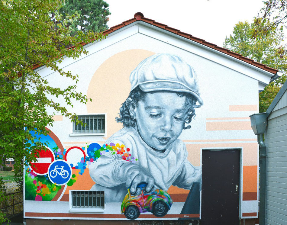 Gestaltung von Fassade zeigt Junge mit buntem Auto und Verkehrsschildern. Graffiti Auftrag in Eschborn bei Frankfurt.