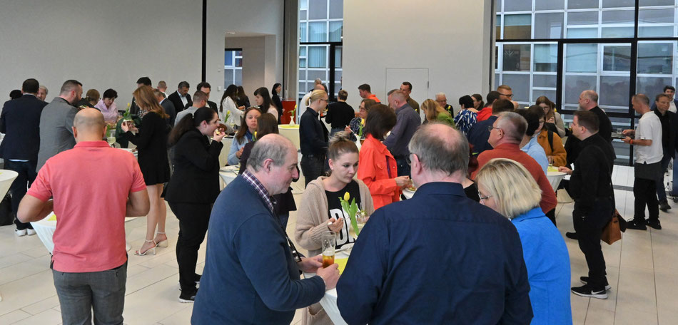 Voller Veranstaltungsraum mit Teilnehmenden an Stehtischen.