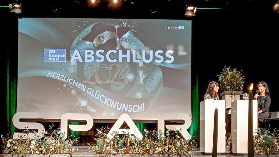 Bühne bei der SPAR-Abschlussfeier mit zwei Rednerinnen an Pult