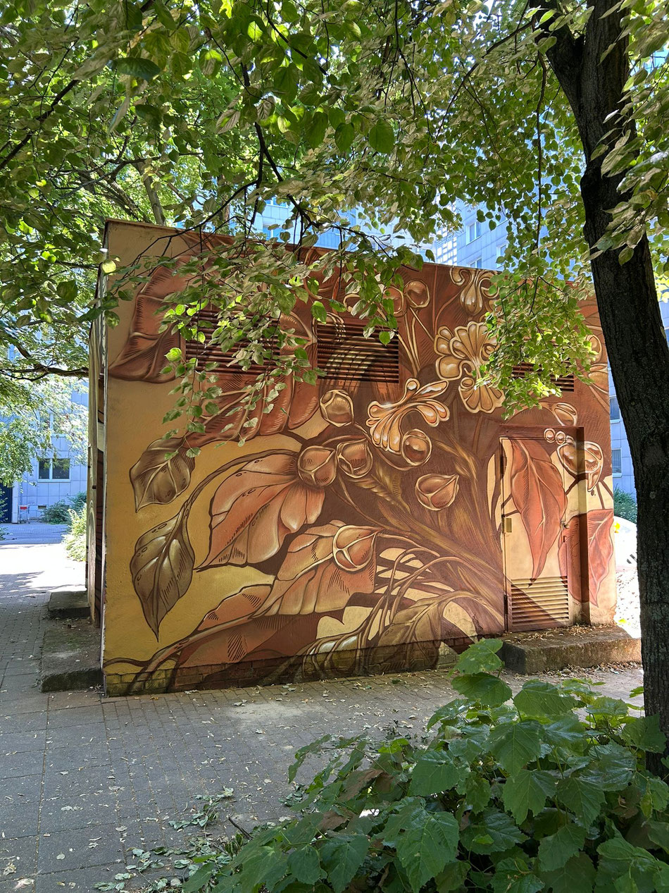 Florale und fotorealistische Fassadenmalerei mit warmen Erdtönen an einer Außenwand, umgesetzt vom Graffitikünstler Berlin.