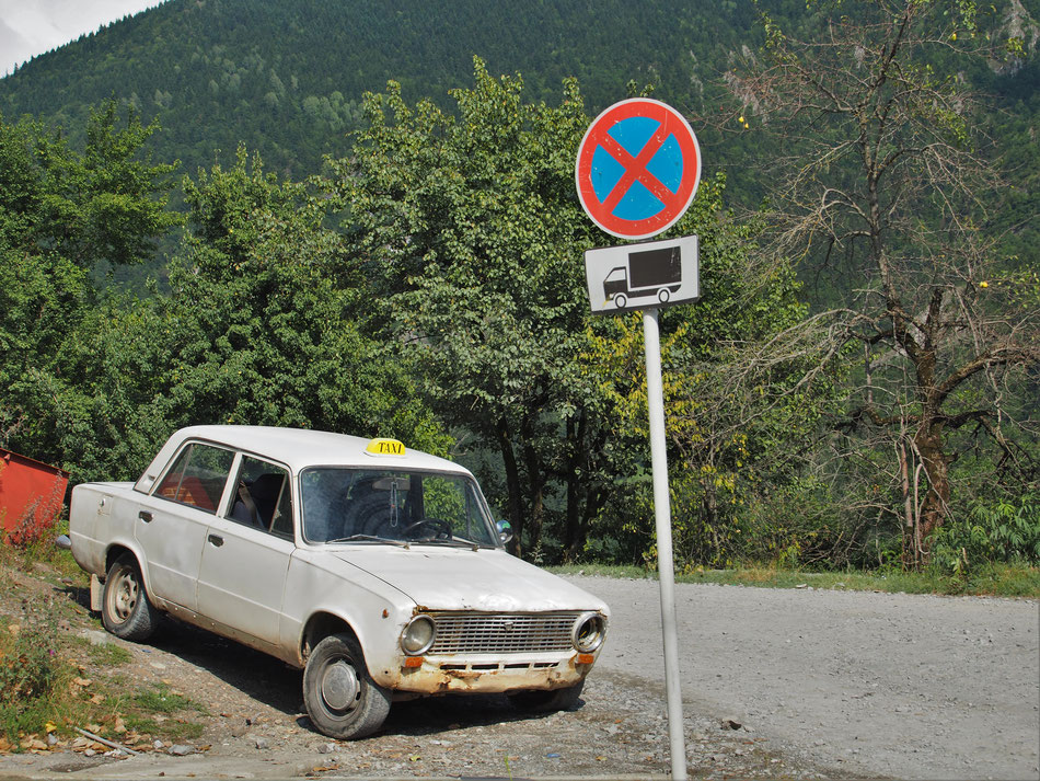 Átlagos állapotú félszemű taxi várja a fuvarját. A mellette lévő leszakadt elejű Micrában (szintén taxis) az öreg szépen húzogatta a vodkásüveget.