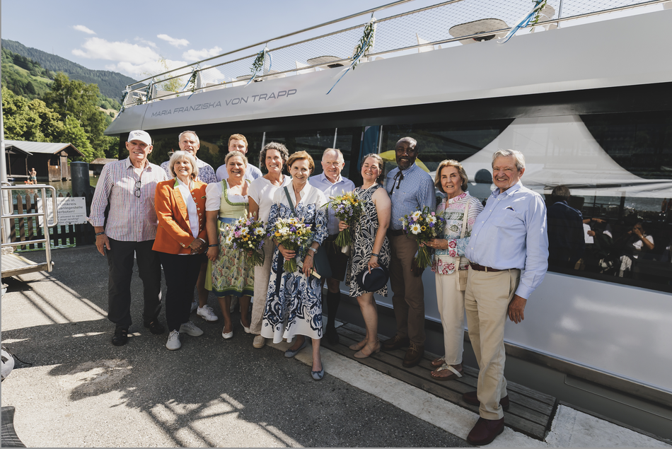 Eine Gruppe von Menschen steht vor einem Schiff, das auf den Namen „Maria Franziska von Trapp“ getauft wurde.
