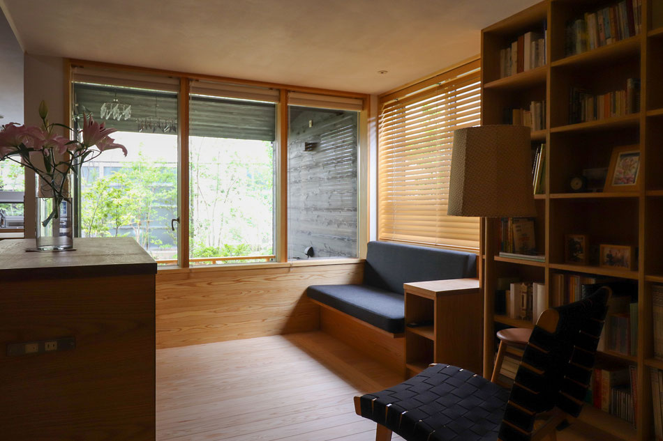 リビングからテラスを通して庭を眺める。造作のソファ・本棚と木製建具で一体感をつくっている。