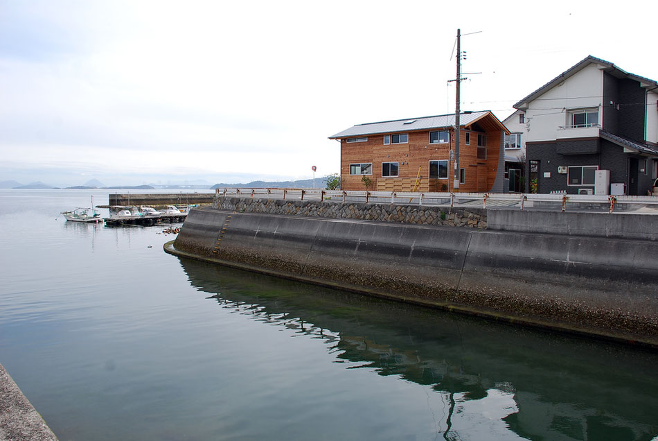 水路対岸から望む。助産院は海を向き、遠く瀬戸大橋や四国が広がる。