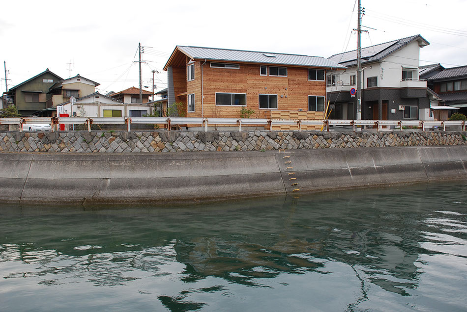 水路越しに助産院をみる。水面の輝きに呼応させた形で屋根板金色を選ぶ。