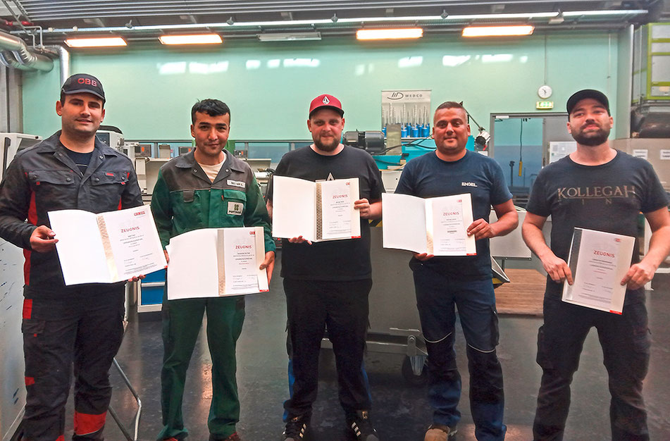Gruppe von Absolvent:innen des Lehrberufs Metallbearbeitung mit Lehrabschlusszeugnissen
