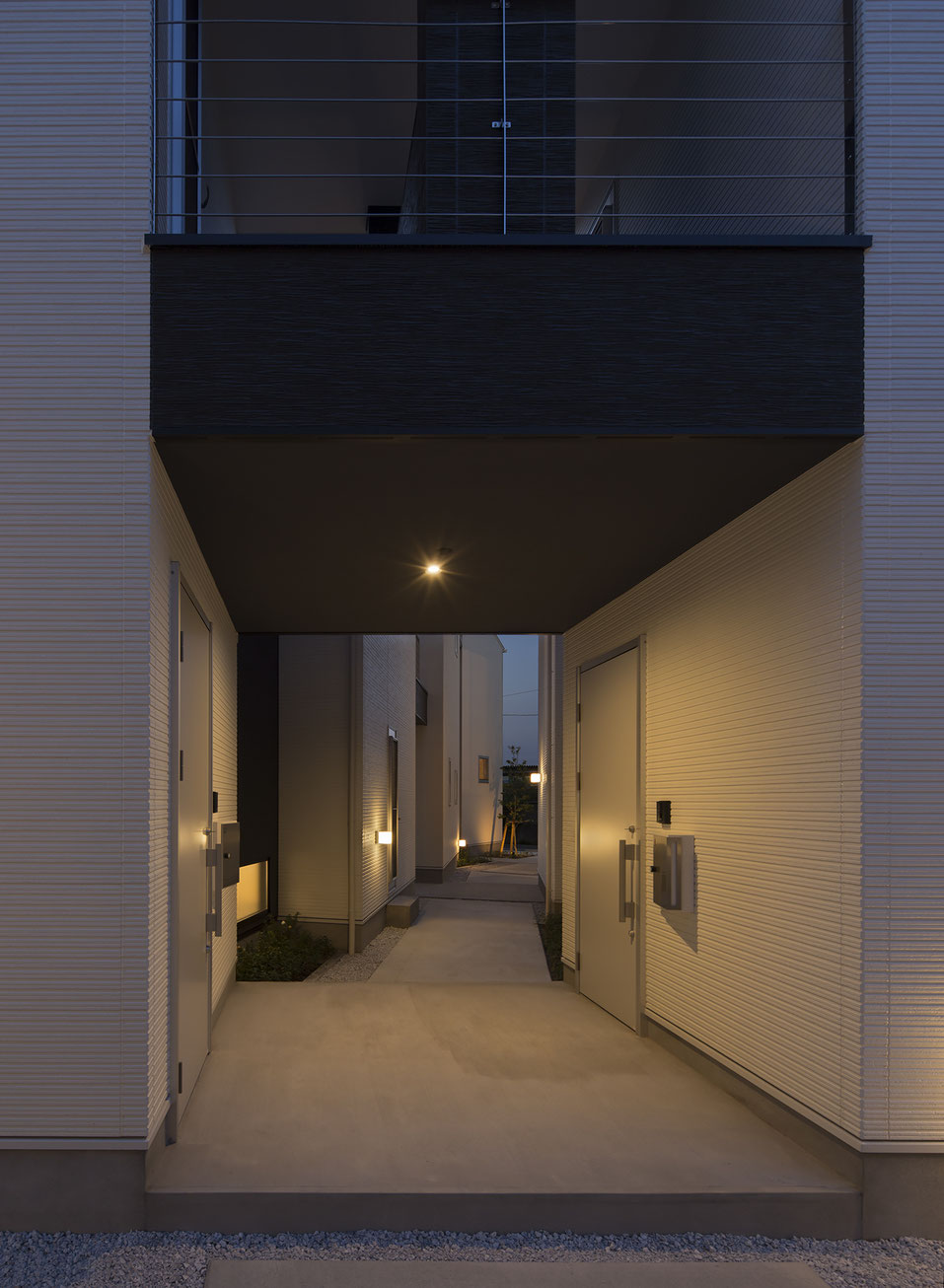 角建築研究室(代表 角大輔 Daisuke Sumi)による福岡県飯塚市の新築木造アパート。各住戸の明かりが漏れる路地空間の夜景写真。