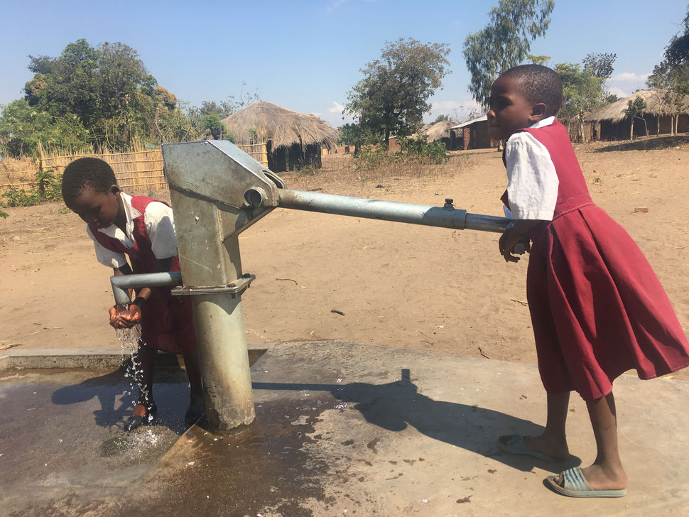 Zwei Schulkinder an einer Wasserpumpe in Kunghongo, Malawi. Landrat Stefan Rößle hat hier den Bau von zwei Klassenräumen finanziert. Foto: Welthungerhilfe.