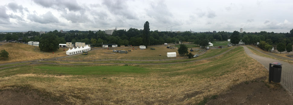 Blick vom Hügel in den Hauptbühnenbereich. Die Bühne wird rechts neben dem großen, langen Baum bis zu dem kleinen Baum rechts von dem weißen Transporter aufgebaut.