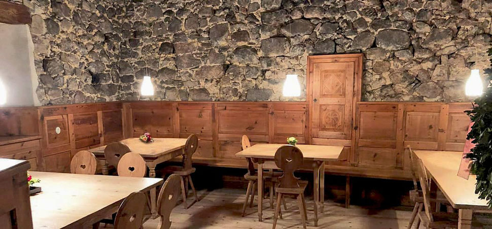 Accogliente stube al Wassererhof di Fiè allo Sciliar con rivestimenti in legno, pareti in pietra naturale e illuminazione suggestiva: l'ambiente ideale per trascorrere tradizionali serate altoatesine.