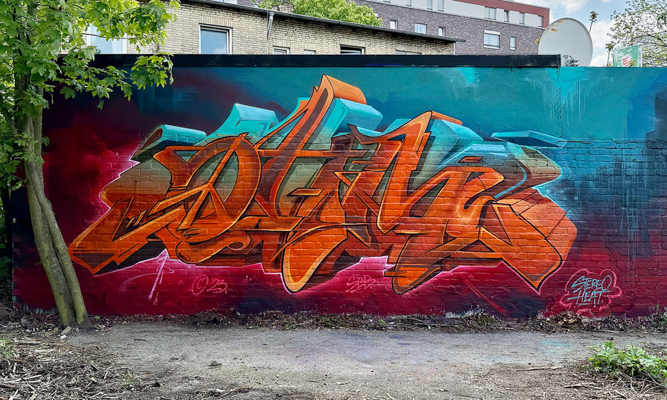 Ein Graffiti in Orange, Beige und Türkis Farben auf einem Stahlblau zu Dunkelrot Verlauf. Gemalt auf einer Wand in Hamburg Barmbek. Zu lesen ist der Name OHM – und das O ist gleichzeitig ein Peace-Symbol.
