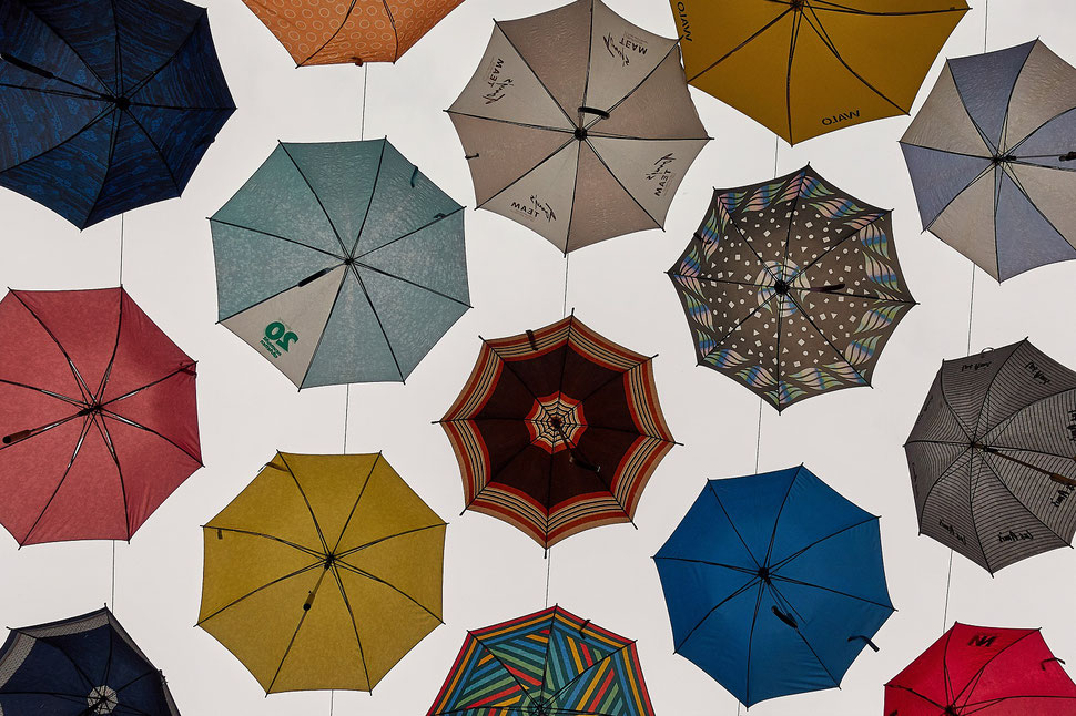 The image shows the photograph of colorful umbrellas from below.