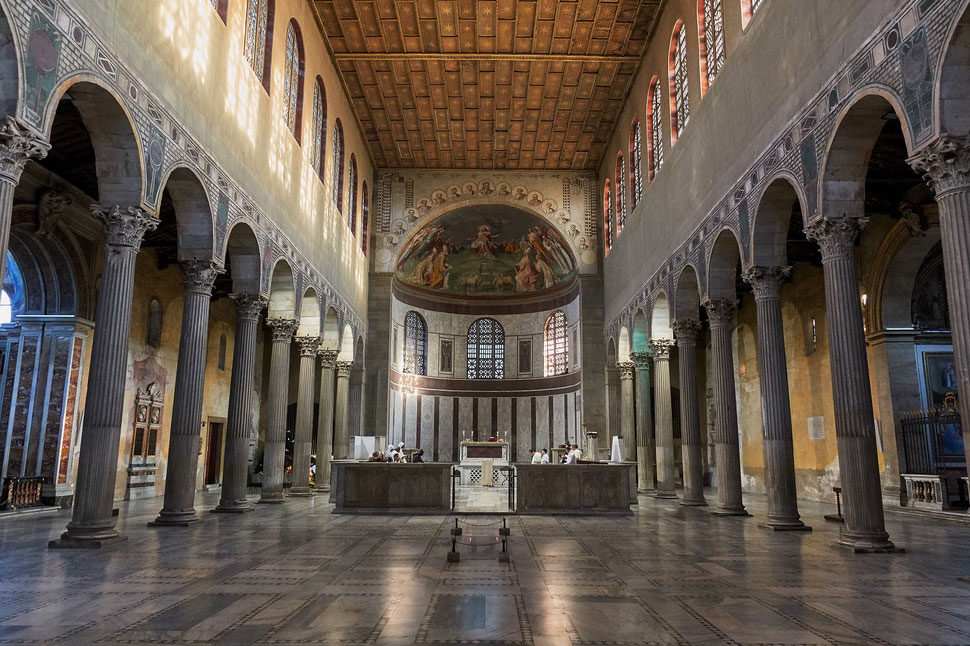 The image shows the photograph of the inside of the Basilica of Saint Sabine, where a sunday morning mass is held.