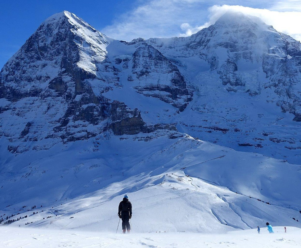 The photograph shows an image of a skier in the foreground and of the impressive north face of the Eiger in the background.