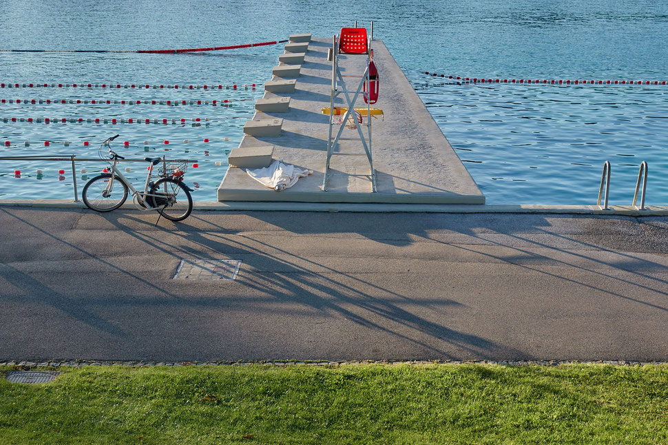 The image shows the photograph of a summer evening in an empty public swimming pool.