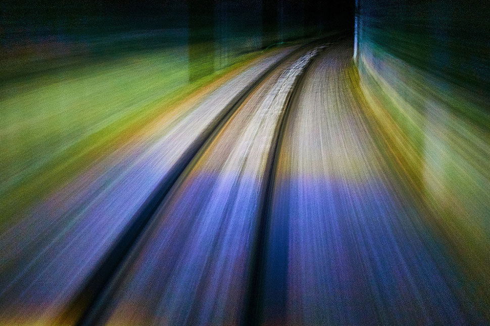 The image shows the long exposure photograph of rail tracks and blurred ground and walls.