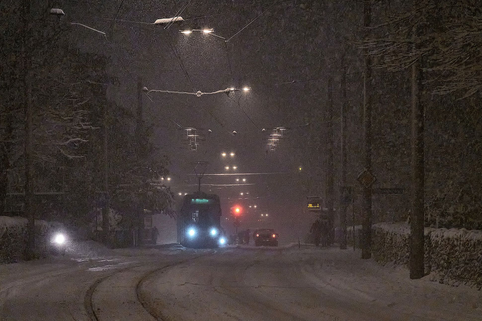The image shows a nocturnal photograph of Bern tram number 7 trveling west through a heavy snowstorm.