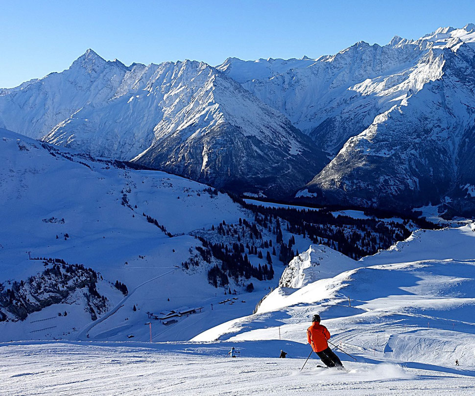 The photograph shows an image of a skier set against the backdrop of a range of mountains. The location is Hochsträss, Haslberg,