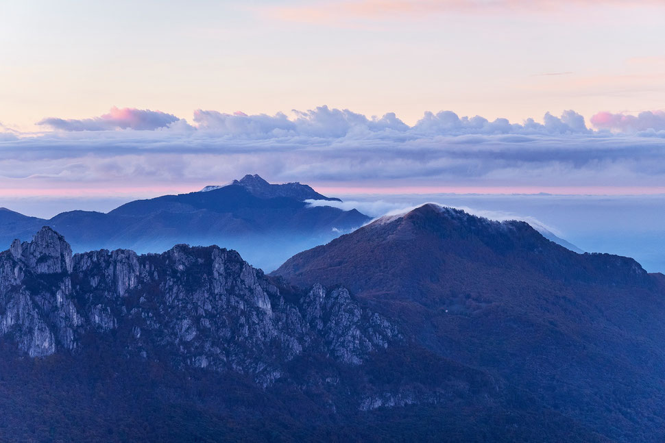 The image shows the photograph of a landscape with mountains and clouds in the soft light of an early Winter morning.