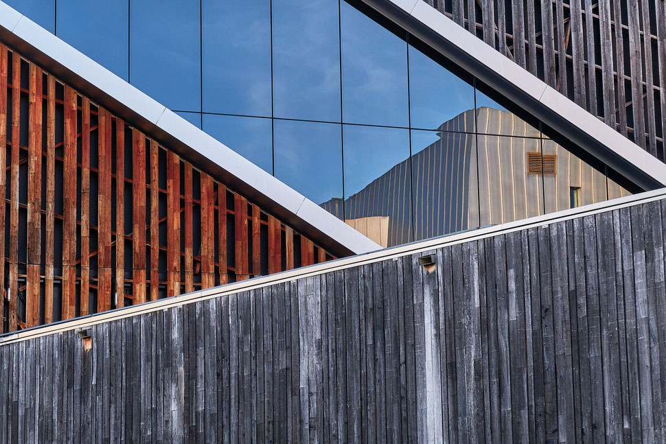 The image shows a close-up photograph of a building with a window, in which another building is reflected.