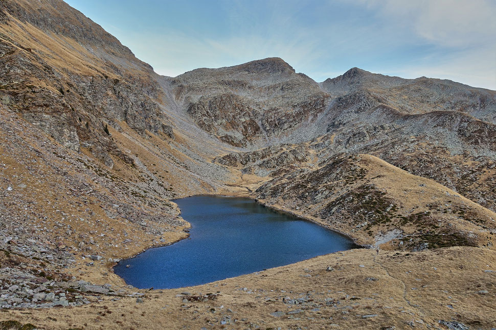 The image shows the photograph of a heart shaped mountain lake in a rugged mountain environment. 