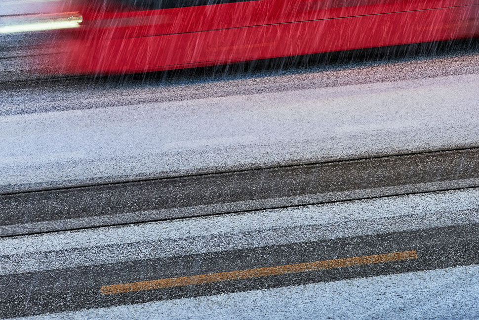 The image shows the photograph of a part of a passing tram and the snow covered street.