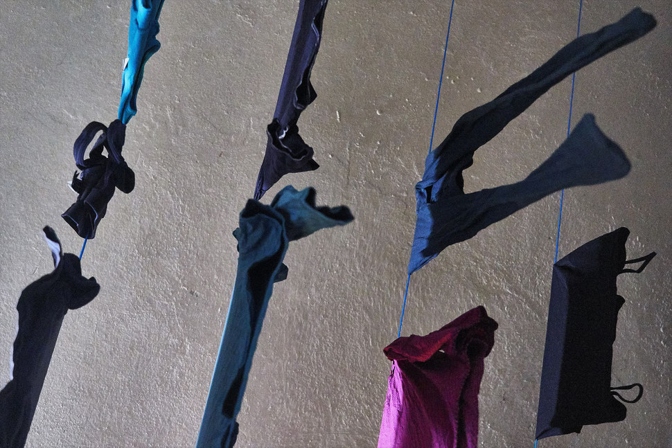The image shows the photograph of drying clothes and the ceiling in a laundry room from below.
